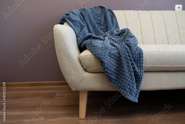 Obraz Cozy beige sofa with a textured blanket draped gently, creating a soft and inviting relaxation spot.