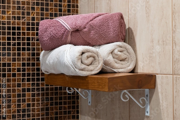 Obraz Softly lit bathroom shelf with folded towels, combining texture and warmth in a clean, inviting space.