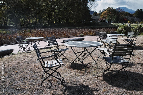 Obraz 秋晴れの空の下、公園に置かれた趣のあるテーブルとイス