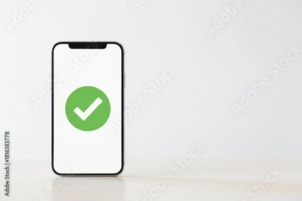 Obraz A phone with a green check mark on it. The phone is sitting on a table. The check mark indicates that the phone is functioning properly