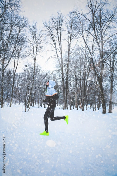 Fototapeta Man exercising / jumping and running in the park filled with snow.