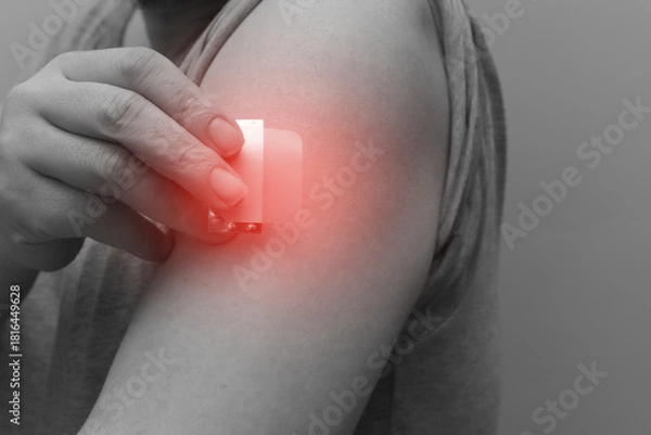 Fototapeta A close-up of a hand applying a nicotine patch to the upper arm. Represents Nicotine Replacement Therapy (NRT) and the user's commitment to quit smoking and pursue better health