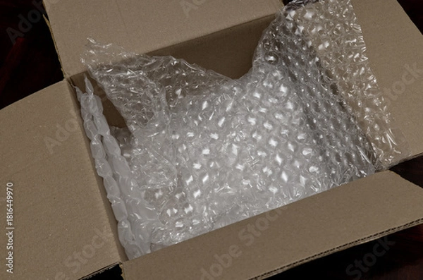 Fototapeta an open brown cardboard box showing clear plastic bubble wrap used as protective packaging material inside. 