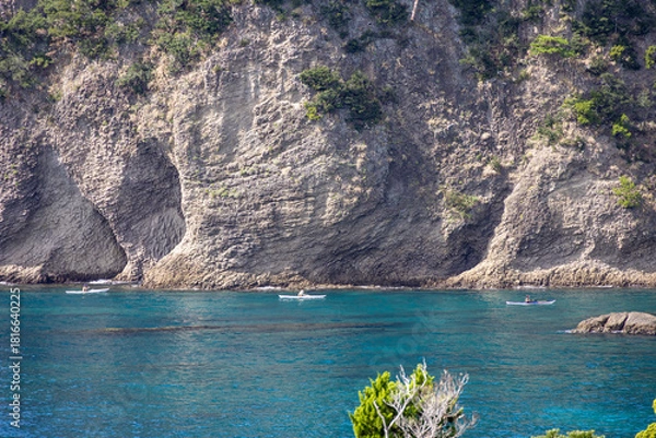 Obraz 紺碧の海の上を行く３隻のカヤックと背後にそびえる海食によって削られた巨大な岩壁