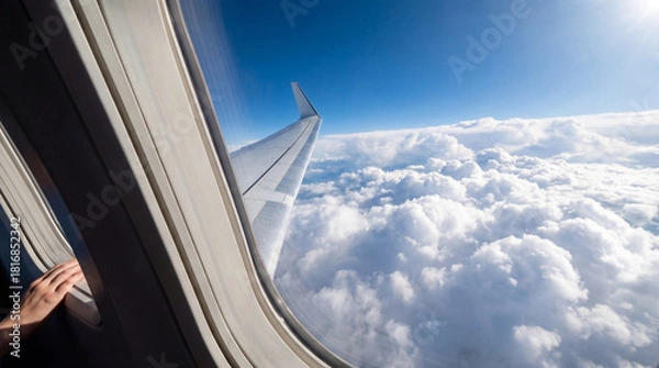 Fototapeta Aerial View of Clouds and Airplane Wing through Window with Passenger Hand
