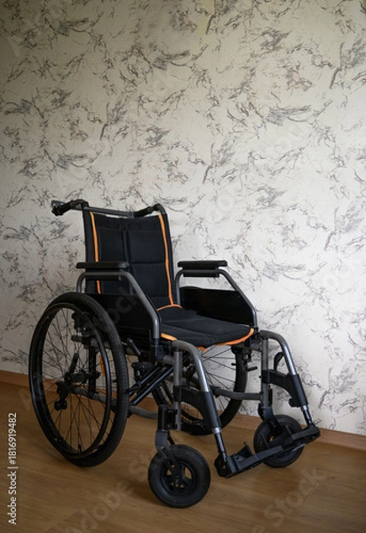 Fototapeta Vertical image of a wheelchair in a clean interior with a light patterned wall and wooden floor. Suitable for healthcare, rehabilitation, mobility assistance, accessibility themes, and medical service