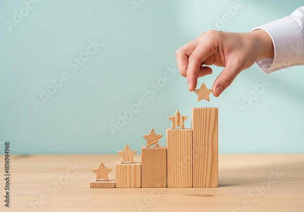 Fototapeta Hand placing a star block on top of a wooden staircase, a professional concept perfect for achieving goals, career growth, and reaching for success