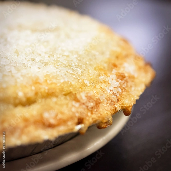 Fototapeta A dramatic close-up of the baked cherry pie's crust, showing the texture of the golden pastry and the thick, sparkling sugar topping in the cafe.