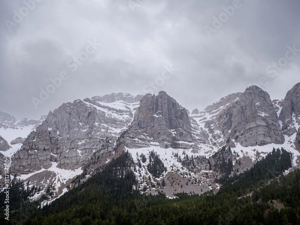 Fototapeta Rugged snow-capped peaks of Sierra del Cadi under gray sky