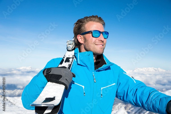 Obraz Young, sexy man is skiing in winter paradise in the alps with a beautiful blue sky and wonderful white snowy mountains 