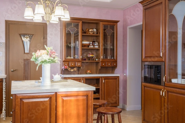 Fototapeta cupboard in  light classic kitchen and vase with flowers on  table
