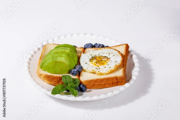 Fototapeta Avocado Toast and Egg in Hole Breakfast with Blueberries - Healthy Morning Meal