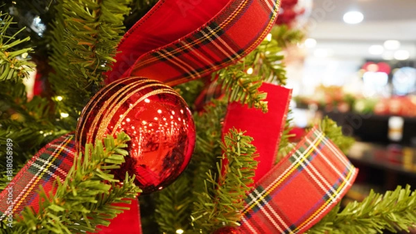 Fototapeta Red Christmas ornament glowing warmly on decorated tree with twinkling lights
