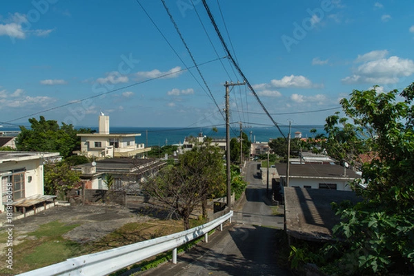 Obraz 快晴の空とエメラルドグリーンの海の見える街並みと下り坂
