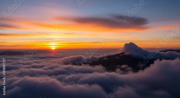 Fototapeta Dramatic sunset over mountain range with layered clouds and orange sky