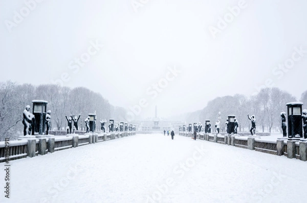 Fototapeta OSLO, January 2015. Some people walking during a snow fall in Vigeland sculpture park or Vigelandpark in Oslo, Norway. Vigeland is located in the Frognerpark in Oslo