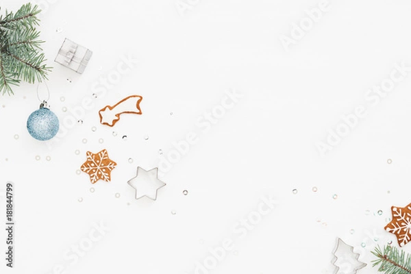 Obraz Holiday background with gingerbread and Christmas decorations on white. Bauble, spruce branch, gift box, baking molds. Christmas and New Year preparations concept. Top view.