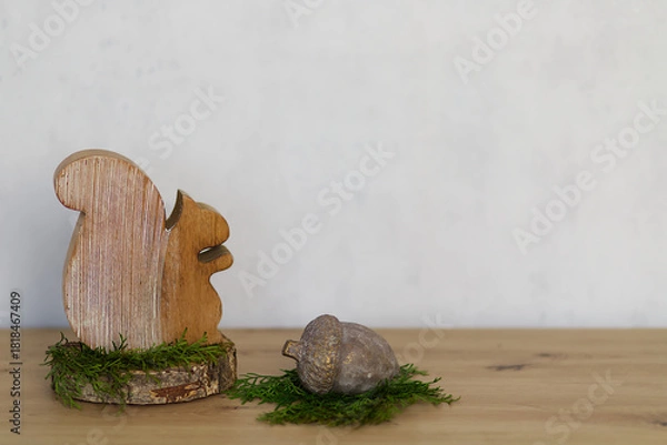 Fototapeta Winter decoration with a wooden squirrel figure and a large metal nut. Decoration with green fir branches on wood against a grey textured background