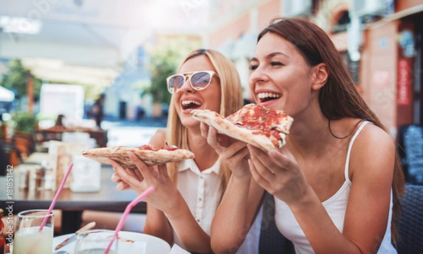 Fototapeta Czas pizzy. Młode dziewczyny jedzenie pizzy w kawiarni. Konsumpcjonizm, styl życia