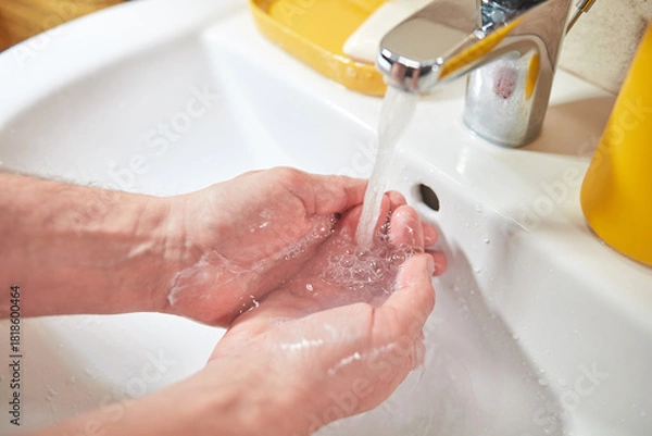 Obraz Human ands are turning the faucet on at home and washing with soap and clean tap water for good personal hygiene.