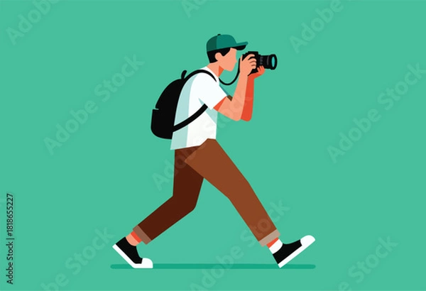 Obraz A person with a cap, backpack, & casual outfit walks while holding a camera, shooting against a teal backdrop