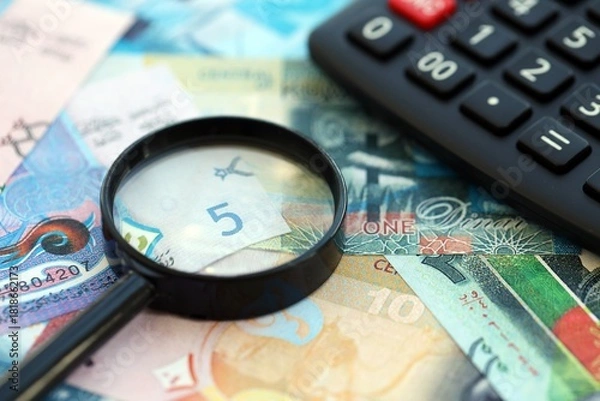 Fototapeta Kuwaiti dinar currency money bills and calculator with magnifying glass close up. The concept of taxation and money count