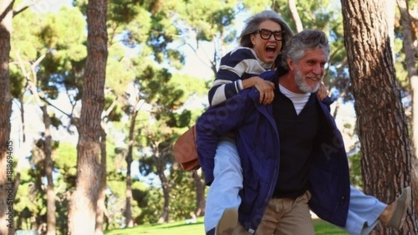 Obraz Senior couple enjoying playful piggyback ride in park