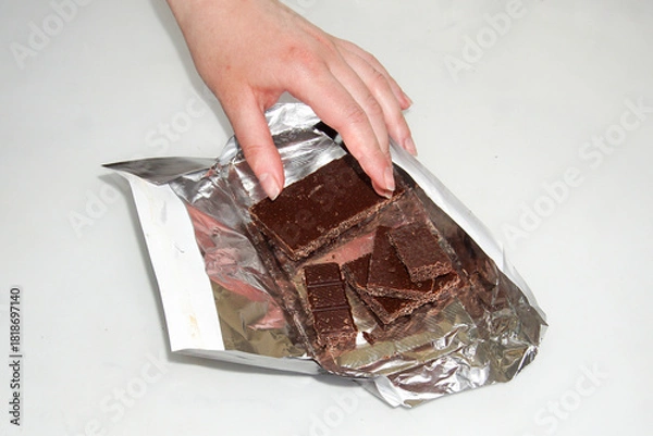 Obraz The girl's hand reaches out and takes a piece of chocolate.