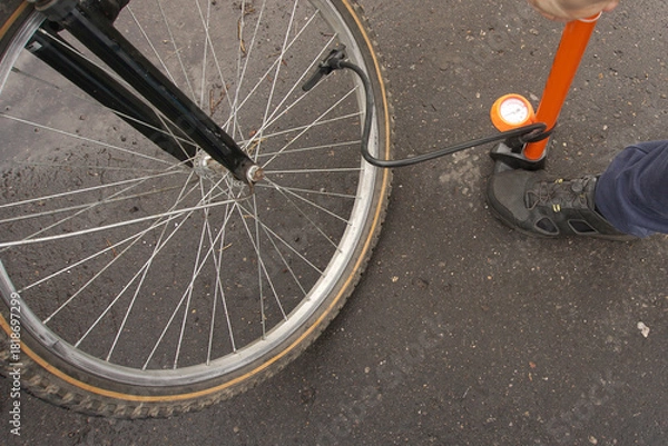 Obraz A cyclist inflates a bicycle wheel with a large pump.