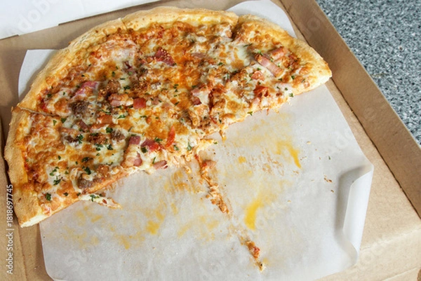 Obraz An open cardboard box with half eaten pizza.