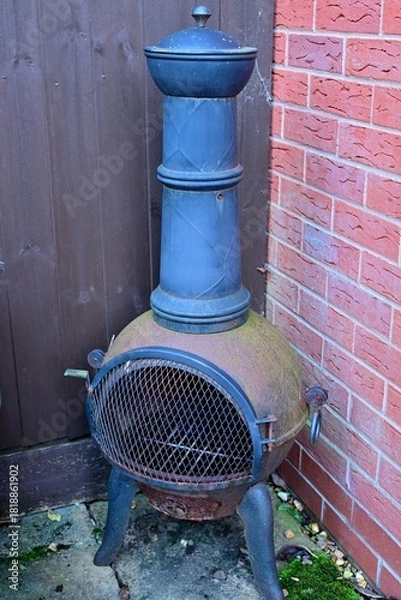 Obraz Rustic Outdoor Chiminea Between Fence and Brick Garden Wall