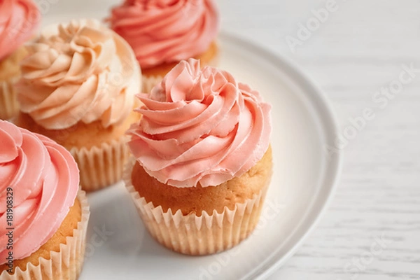 Fototapeta Plate with yummy cupcakes on wooden table