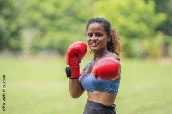 Obraz Smiling woman in boxing gloves punching towards camera, confident action, business engagement, and female empowerment