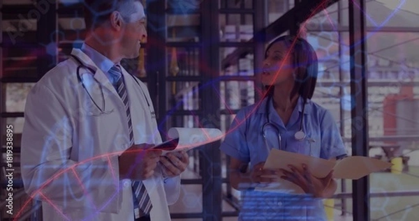 Obraz Reviewing documents doctor in coat and nurse in scrubs at clinic corridor, stethoscopes DNA overlay