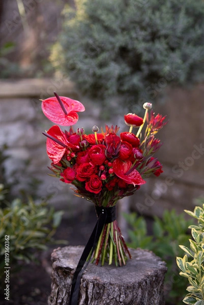 Fototapeta Elegant Red Bouquet With Anthuriums and Roses on Tree Stump Outdoors