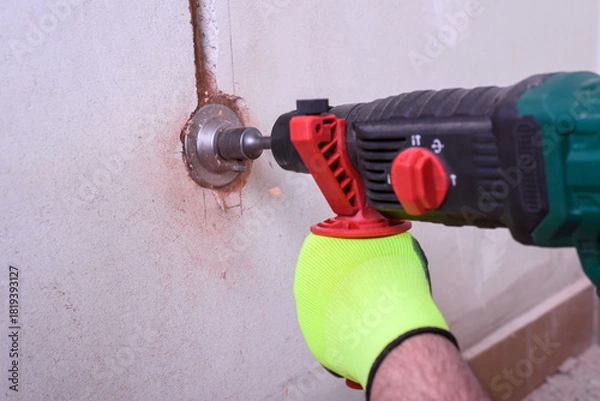 Obraz Contractor with hammer drill doing hole for socket