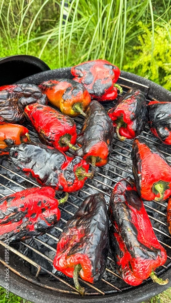 Fototapeta Charred crimson peppers sizzle atop the grill, summoning the fiery spirit of La Tomatina, embracing rustic culinary artistry