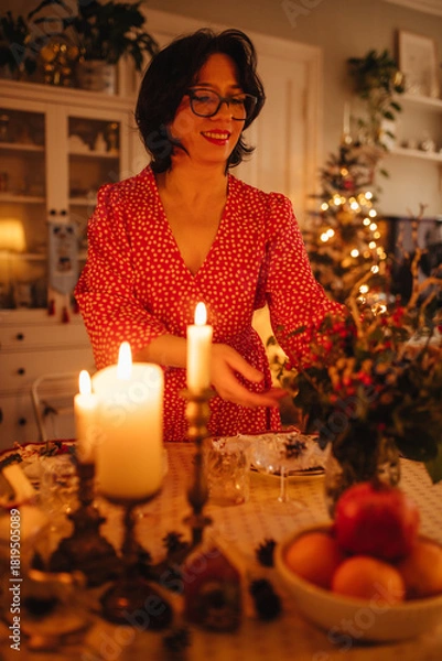 Obraz A woman is setting the table for Christmas dinner