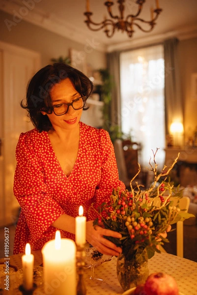 Obraz A woman is setting the table for Christmas dinner