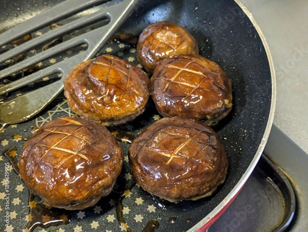 Obraz フライパンで焼かれたしいたけの肉詰め料理 美味しい照り焼き味