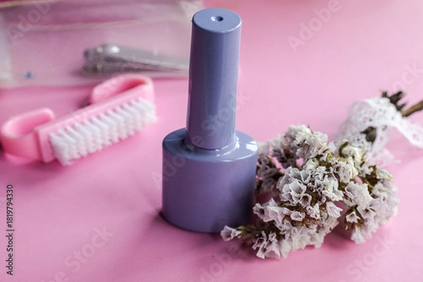 Fototapeta Pastel lilac nail polish bottle on a pink background, featuring a nail brush, manicure toolkit, and delicate dried flowers for a self care beauty routine