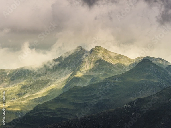 Fototapeta Green mountains in sun and shadow, twin peaks, covered in clouds, alps, Southtirol