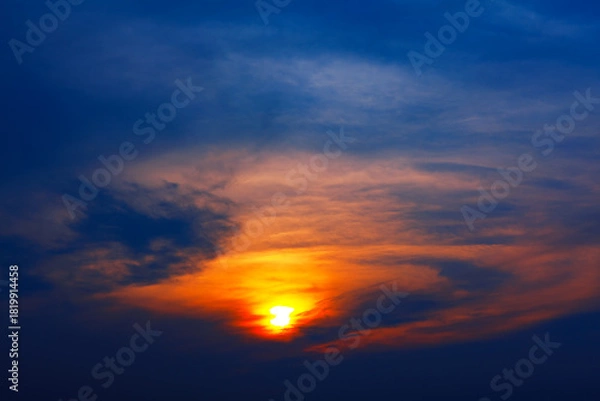 Obraz Sky glows with fiery orange and golden hues as sun peeks through scattered clouds, casting dramatic light across the horizon. Deep blue gradient crowns scene, enhancing its vivid contrast