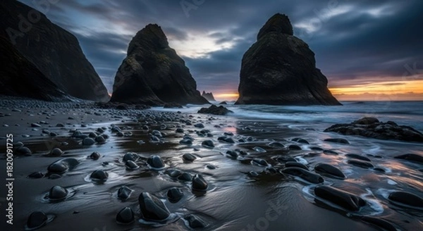 Fototapeta Dramatic seascape featuring towering rock formations at dusk along a pebble beach