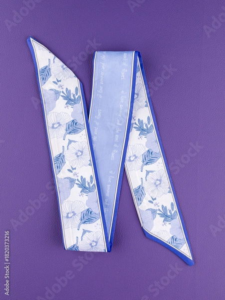 Obraz Close-up of a blue silk ribbon bow with a floral pattern on a purple background