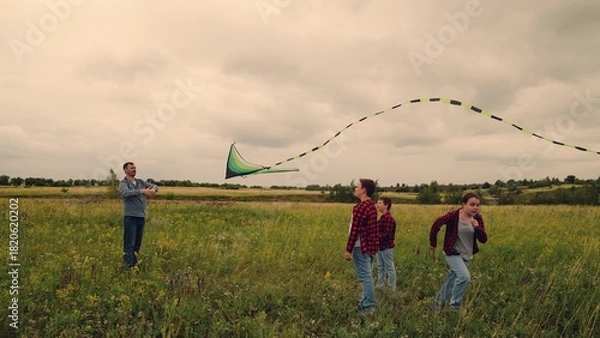 Fototapeta Dad flying kite with two kids, children dreaming of touching the sky, outdoor playtime filled with giggles, father teaching and guiding, brother and sister chase dreams, green field adventure, sky