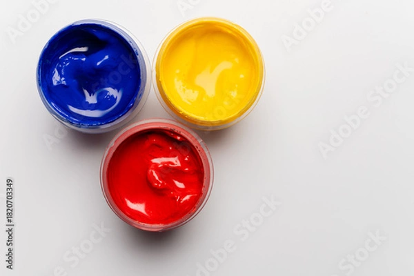 Obraz Jars of multi-colored gouache on a white background. Blue, red, and yellow traffic light colors.