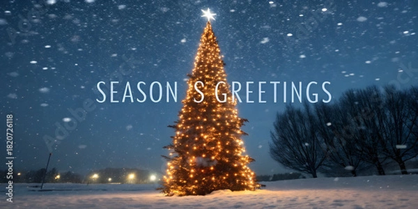 Obraz Christmas background image showing glowing outdoor Christmas tree covered with golden lights amid heavy snowfall under dark blue winter sky.
