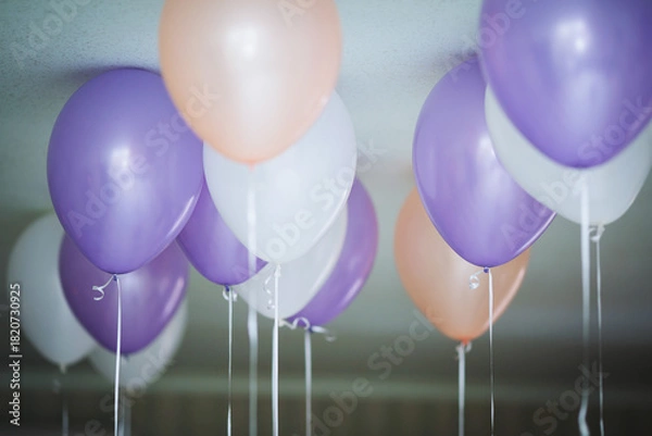 Obraz Colorful balloons in purple, peach, and white floating from the ceiling in a festive setting during a celebration or party