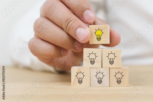 Fototapeta Creative idea, solution and innovation concept. Idea generation and screening for product development process. Wooden blocks with light bulb and yellow color icons on clean background and copy space